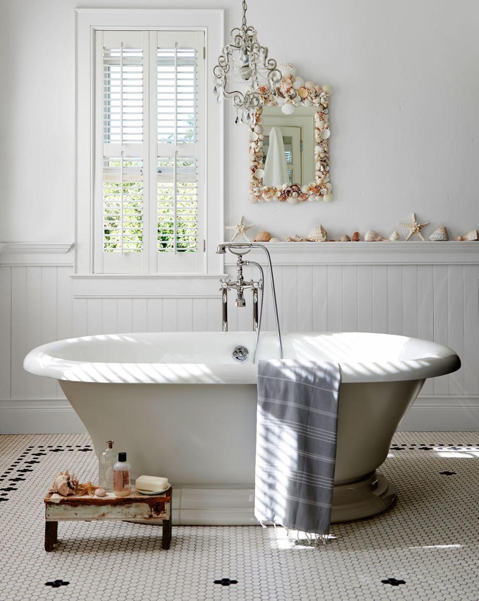 white bathroom with black and white tiled floor and shells lining the wainscoting