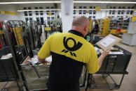 A postman of the German postal and logistics group Deutsche Post sorts mail at a sorting office in Berlin's Mitte district, December 4, 2013. Deutsche Post, the world's number one postal and logistics group, transported around 18 billion letters in 2012. REUTERS/Fabrizio Bensch (GERMANY - Tags: BUSINESS EMPLOYMENT)