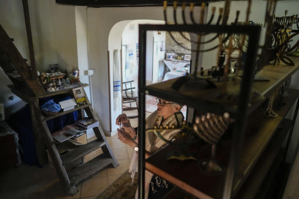 Rabbi Barbara Aiello shows her collection of religious items in her "Ner Tamid del Sud" (The Eternal Light of the South) synagogue in Serrastretta, southern Italy, Friday, July 8, 2022. From a rustic, tiny synagogue she fashioned from her family's ancestral home in this mountain village, American rabbi Aiello is keeping a promise made to her Italian-born father: to reconnect people in this southern region of Calabria to their Jewish roots, links nearly severed five centuries ago when the Inquisition forced Jews to convert to Christianity. (AP Photo/Andrew Medichini)