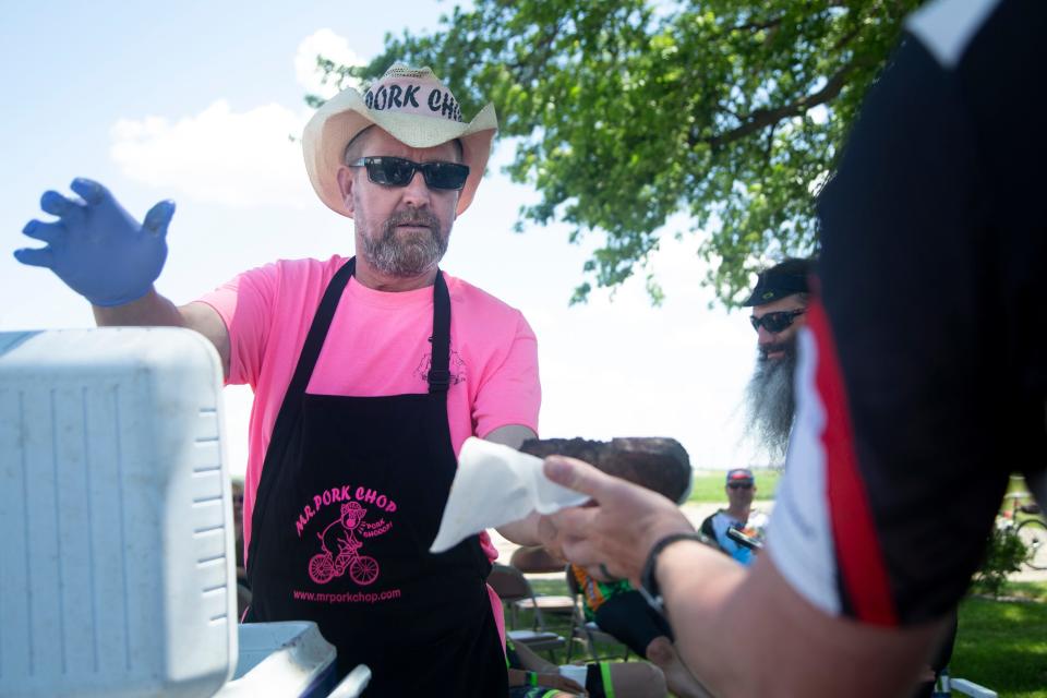 Matt Bernhard, Mr. Pork Chop Jr., hands a pork chop to a rider on the RAGBRAI route inspection ride.