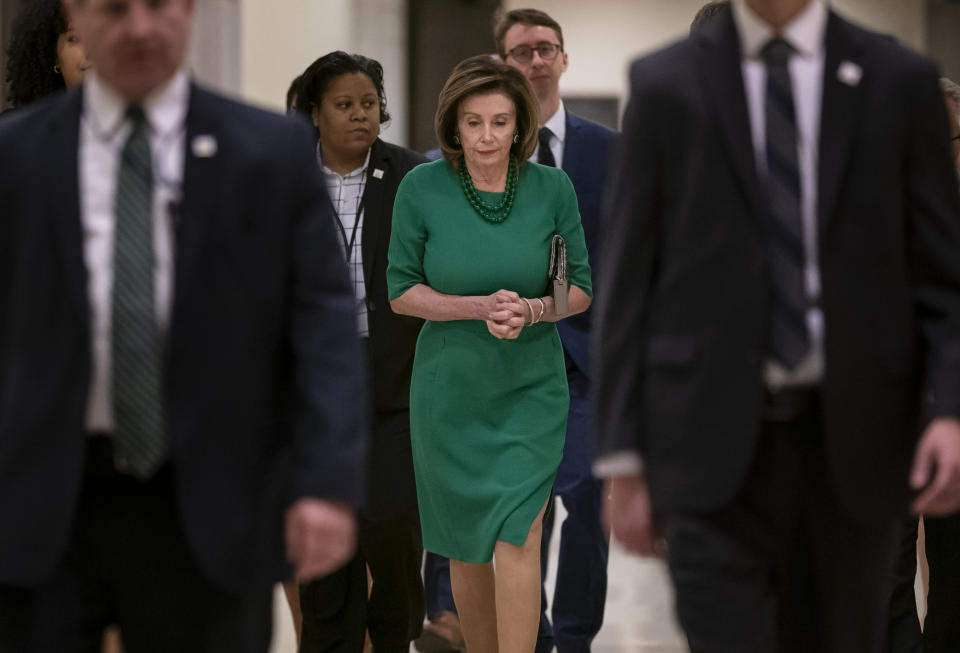 Flanked by her security detail and aides, Speaker of the House Nancy Pelosi, D-Calif., arrives to update reporters as lawmakers continue work on a coronavirus aid package, on Capitol Hill in Washington, Thursday, March 12, 2020. (AP Photo/J. Scott Applewhite)