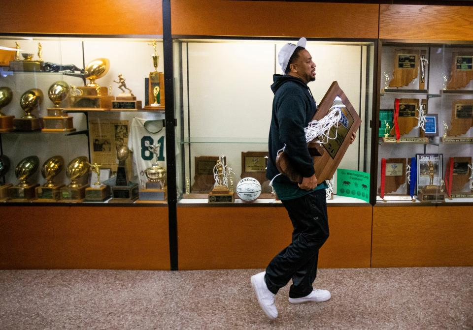 Washington head coach Steve Reynolds walks past an empty trophy case with the state championship trophy during a welcome home celebration for the state-title winning girls basketball team Sunday, Feb. 27, 2022 at Washington High School. 