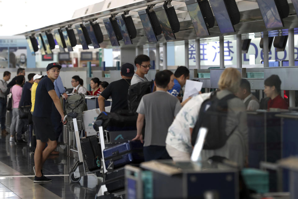 Travellers check in on their flights at the airport in Hong Kong, Wednesday, Aug. 14, 2019. Flight operations resumed at the airport Wednesday morning after two days of disruptions marked by outbursts of violence highlighting the hardening positions of pro-democracy protesters and the authorities in the Chinese city that's a major international travel hub. (AP Photo/Vincent Thian)