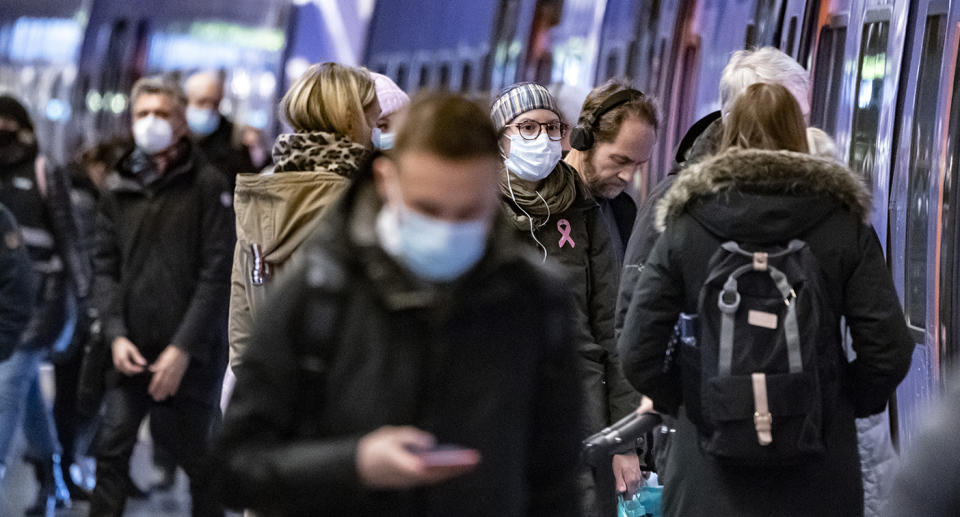 People walking in a busy street in winter wearing face masks.