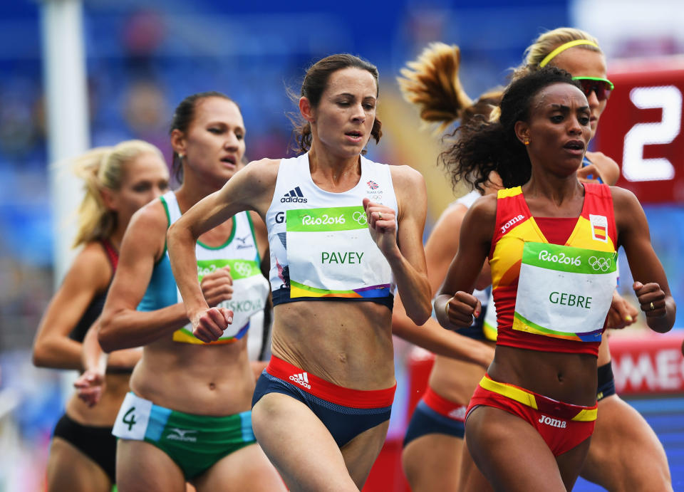 Grupo de mujeres atletas corriendo una prueba de resistencia en un estadio.