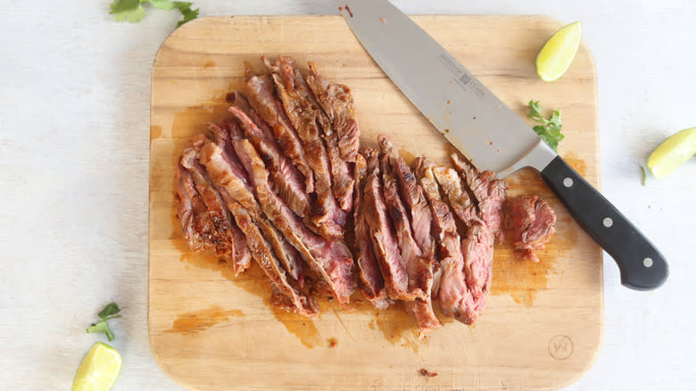 sliced steak on a cutting board with knife