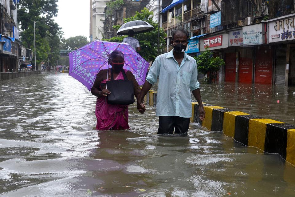 Senior citizens wade in knee deep water along a flooded road during a heavy monsoon rainfall in Mumbai on August 4, 2020. (Photo by SUJIT JAISWAL/AFP via Getty Images)