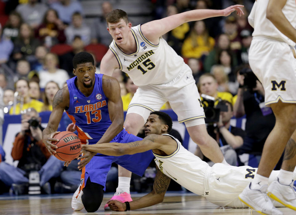 <p>Michigan’s Charles Matthews, bottom, Jon Teske (15) and Florida’s Kevarrius Hayes (13) scramble for the ball during the first half of a second round men’s college basketball game in the NCAA Tournament, in Des Moines, Iowa, Saturday, March 23, 2019. (AP Photo/Nati Harnik) </p>