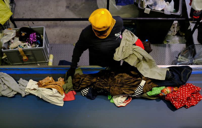 La trabajadora Emelia, ghanesa de 40 años, participante en un programa de la fundación "Formació i Treball" ("Formación y Trabajo"), cuyo objetivo es promover la contratación de personas desempleadas especialmente vulnerables, como los inmigrantes, separa y clasifica ropa usada para empaquetar en un almacén de Sant Esteve Sesrovires, a las afueras de Barcelona, Cataluña, España