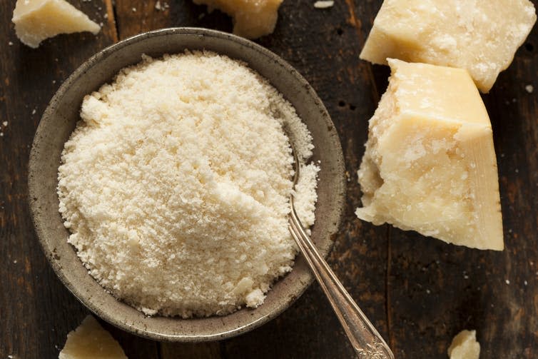 Bowl of parmesan cheese next to a couple of wedges