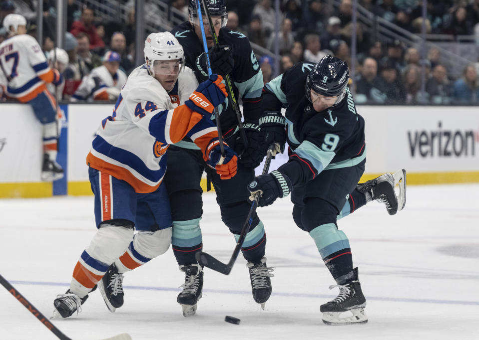 Seattle Kraken forward Ryan Donato, right, takes a shot on goal as forward Daniel Spring, center attempts to screen New York Islanders forward Jean-Gabriel Pageau during the second period of an NHL hockey game, Sunday, Jan. 1, 2023, in Seattle. (AP Photo/Stephen Brashear)