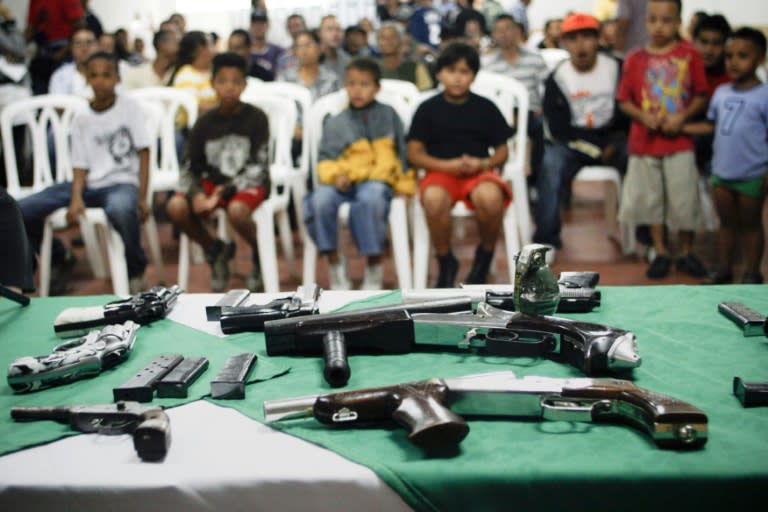 A group of children stare at arms, handed in by 40 youngsters in Medellin, Colombia, during a disarmament initiative in 2009