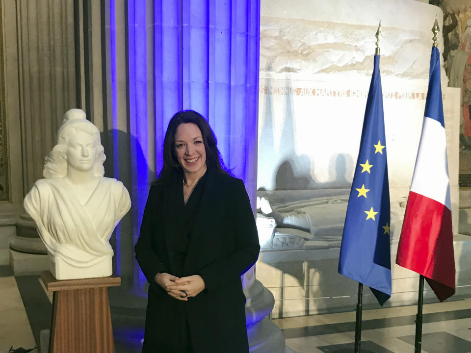 Britain's Catherine Norris Trent poses next to a bust of Marianne, left, symbol of the French Republic, and the French, right, and European flags after a naturalization ceremony in Paris' Pantheon monument, Thursday, March 21, 2019. With the looming Brexit deadline, the 38-year-old mother of two who's lived in the French capital for over a decade was one of dozens of newly-minted French nationals attending the cermony. (AP Photo/Thomas Admason)