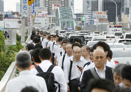 People walk on a bridge over Yodo River after public transportation services were suspended for damage checks after an earthquake in Osaka, Osaka Prefecture, Osaka prefecture, western Japan, in this photo taken by Kyodo June 18, 2018. Mandatory credit Kyodo/via REUTERS