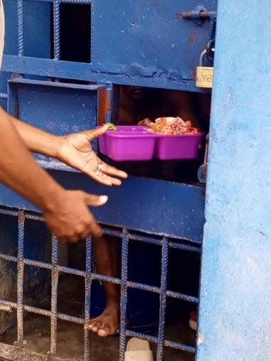 Health through walls staff bringing meals to prisoners.