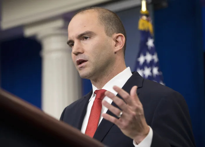 Ben Rhodes stands at a podium in front of an American flag.