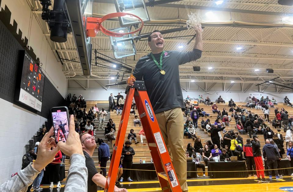 Olentangy Orange coach Anthony Calo holds up the net to celebrate a 60-40 win over Reynoldsburg in a Division I district final Saturday at Ohio Dominican.