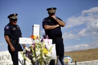 Oficiales de la Policía de Aurora, Colorado, Estados Unidos, miran la cruz de la víctima Gordon Cowden en el memorial frente al cine donde murió, junto con otras 11 personas el 20 de julio de 2012. (AFP/GETTY IMAGES | joshua lott)