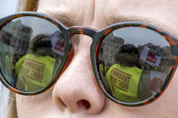 Demonstrators are reflected in the glasses of a participant in Halle/Saale, Germany, Thursday, March 23, 2023. German unions are calling on thousands of workers across the country's transport system to stage a one-day strike on Monday that is expected to bring widespread disruption to planes, trains and local transit. (Hendrik Schmidt/dpa/dpa via AP)