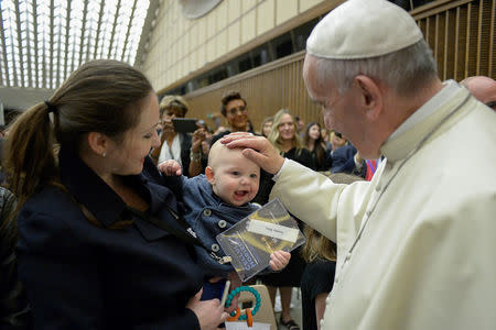 Pope Francis waves a child during a conference on regenerative medicine in Paul VI hall at the Vatican April 29, 2016 Osservatore Romano Handout via Reuters