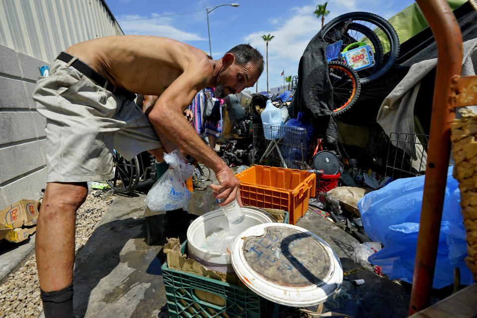 FILE - Kevin Hendershot pours ice into a bucket outside his tent in "The Zone," homeless encampment, July 14, 2023, in downtown Phoenix. The United States is ill-prepared to ensure housing and care for the swelling ranks of America's older people. That's the conclusion of a new report being released Thursday by Harvard University’s Joint Center for Housing Studies. (AP Photo/Matt York, File)