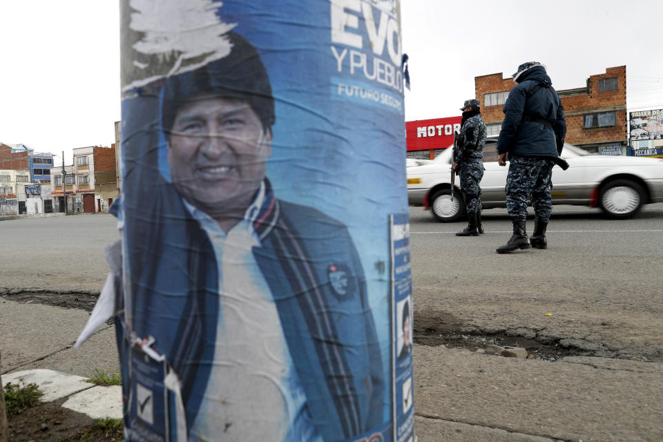 A torn electoral poster of former President Evo Morales covers a street lamp post as soldiers control traffic in El Alto, on the outskirts of La Paz, Bolivia, Tuesday, Nov. 12, 2019. Bolivia faced political vacuum Tuesday, while Morales fled the country on a Mexican plane following weeks of protests fed by allegations of electoral fraud in the Oct. 20 presidential election that he claimed to have won. (AP Photo/Natacha Pisarenko)