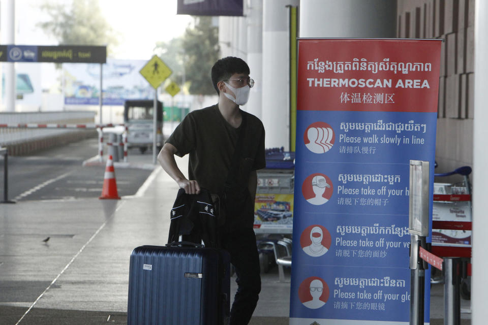 FILE - In this April 3, 2020, file photo, a tourist wearing a face mask enters an area of thermo scan at the quiet Phnom Penh International Airport in Phnom Penh, Cambodia. Cambodia's government announced plans Tuesday, Oct. 26, 2021 to reopen the country in several stages to fully vaccinated foreign tourists starting from the end of next month. (AP Photo/Heng Sinith, File)