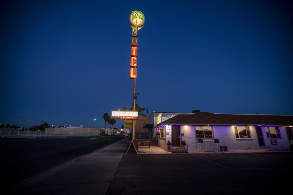 A red neon sign that says MOTEL stands next to a building