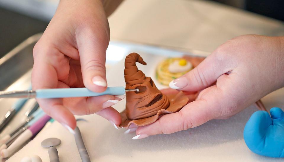 Cake designer Michelle Scurio, of Weymouth, works on details for a cake by sculpting the sorting hat from "Harry Potter"on Wednesday, Jan. 11, 2023.