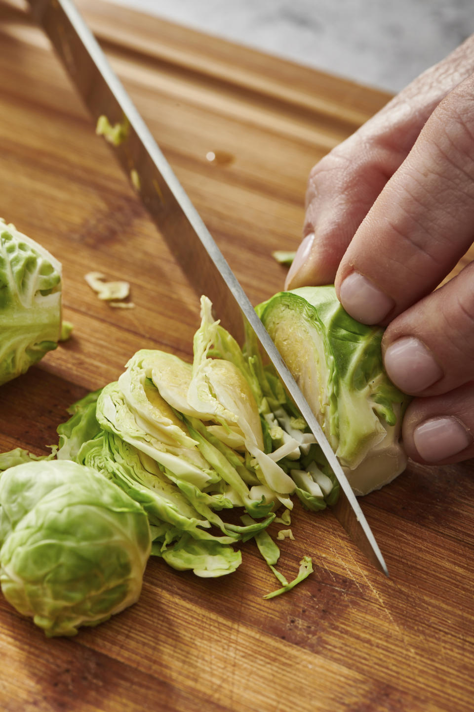 This image provided by Cheyenne Cohen shows Brussel sprouts being sliced on a chopping board. Brussels sprouts are often cooked as a side dish, especially during the cold weather months. They are particularly popular as part of holiday meals such as Thanksgiving and Christmas. And if you think you don't like Brussels sprouts, I'm here to say AP food writer Katie Workman says you just haven't had them prepared well. (Cheyenne Cohen via AP)