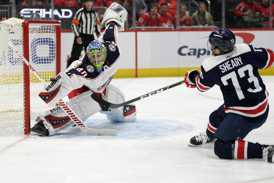 Columbus Blue Jackets goaltender Daniil Tarasov (40) deflects the puck against Washington Capitals left wing Conor Sheary (73) during the first period of an NHL hockey game, Saturday, Dec. 4, 2021, in Washington. (AP Photo/Nick Wass)