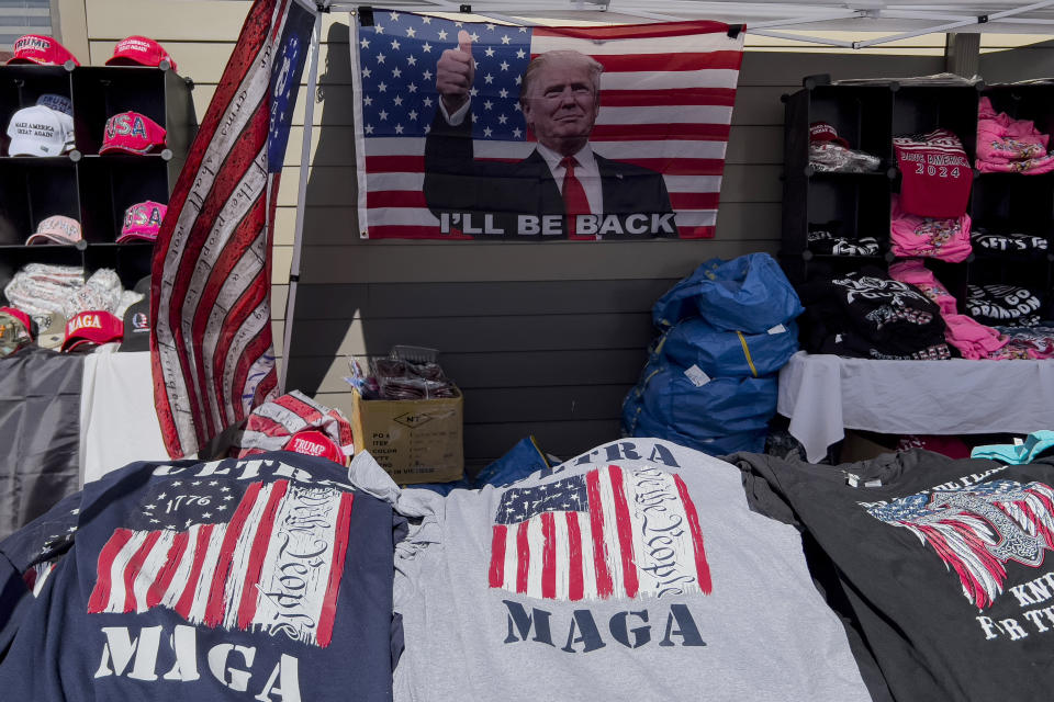 MAGA merchandise and a U.S. flag decorated with an image of former President Donald Trump that reads "I'll Be Back" are displayed for sale during the ReAwaken America tour at Cornerstone Church, in Batavia, N.Y., Saturday, Aug. 13, 2022. Michael Flynn, a retired three-star general who served as Trump's national security adviser, has drawn together election deniers, mask and vaccine opponents, insurrectionists, Proud Boys, and elected officials and leaders in state and local Republican parties. Along the way, AP and Frontline documented, Flynn and his companies have earned hundreds of thousands of dollars for his efforts. (AP Photo/Carolyn Kaster)