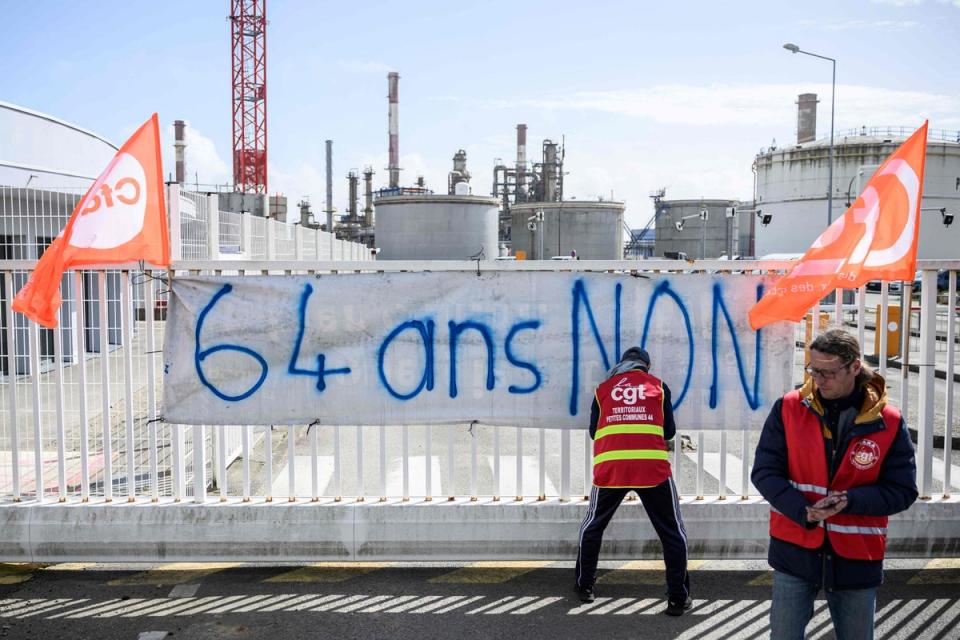 TotalEnergie workers and union members attach a banner reading 