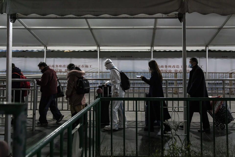 Los pasajeros, incluido uno que viste equipo de protección de cuerpo completo, en la estación del tren de Shánghai, en China, el 14 de diciembre de 2022. (Qilai Shen/The New York Times)
