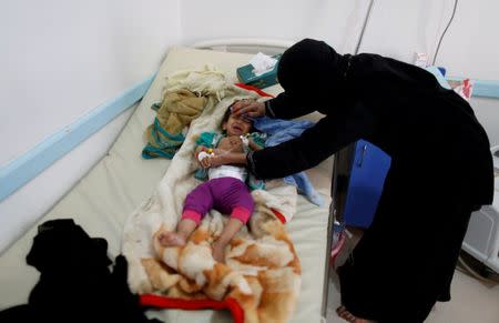 FILE PHOTO - A woman helps her son as he lies on a bed at a cholera treatment center in Sanaa, Yemen June 6, 2017. REUTERS/Khaled Abdullah