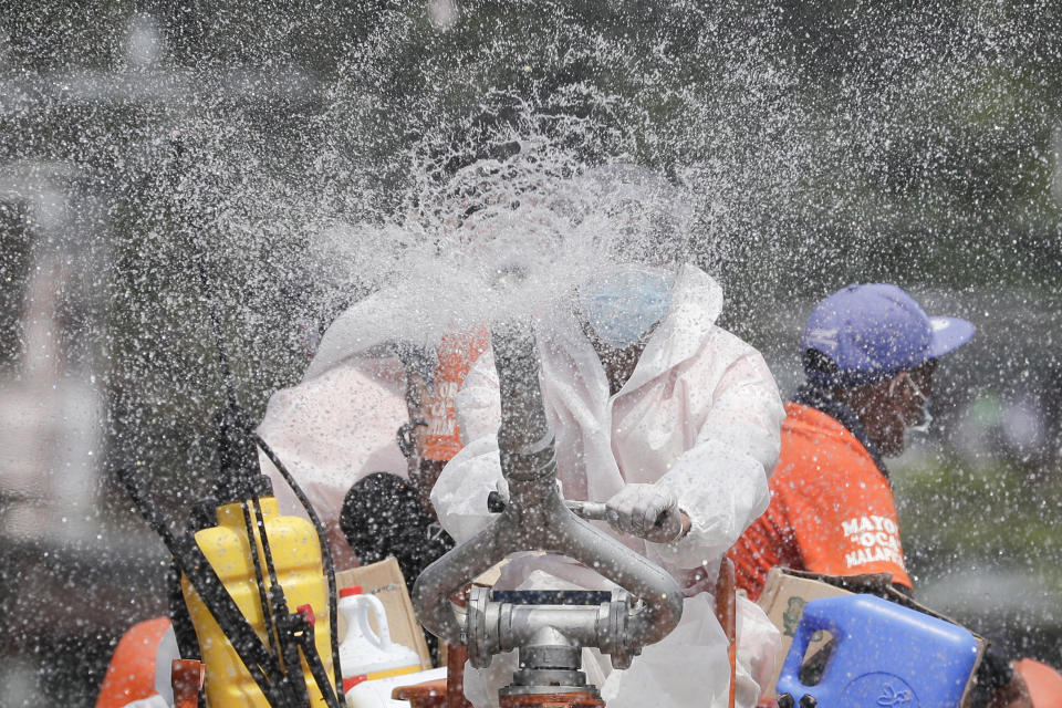 A man disinfects an area placed under stricter lockdown measures to curb the spread of COVID-19 in Caloocan city, Philippines on Friday, Aug. 14, 2020. The capital and outlying provinces is still under lockdown due to rising COVID-19 cases. (AP Photo/Aaron Favila)