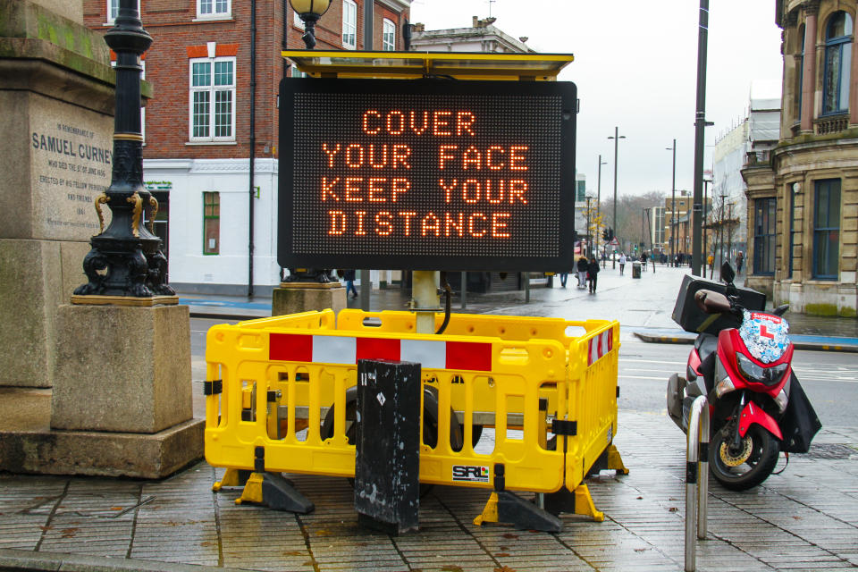 LONDON, UNITED KINGDOM - 2020/12/22: A 'Cover Your Face Keep Your Distance' electronic billboard on the Broadway in Stratford. London and parts of southeast England were put into Tier 4, a tightened measure due to the high presence of the new covid 19 strain. In England, only households living outside a Tier 4 area will be allowed to mix for Christmas and only on Christmas Day. The tier 4 measures are to be reviewed after 30th December. (Photo by David Mbiyu/SOPA Images/LightRocket via Getty Images)