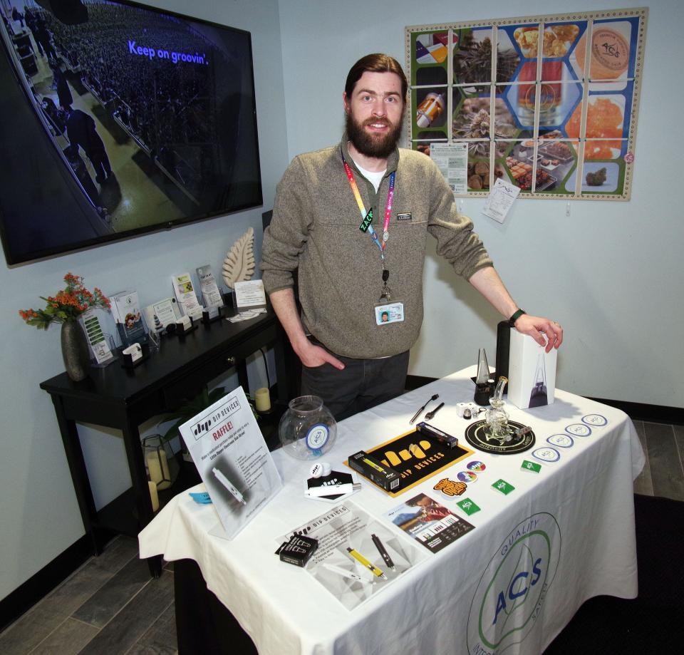Zak Petti of Weymouth, who usually works at the ACS dispensary in Hull, prepares a display of accessories for the use of cannabis, with pens, glassware and other items at thee ACS dispensary in Bridgewater on Wednesday, March 6, 2024.