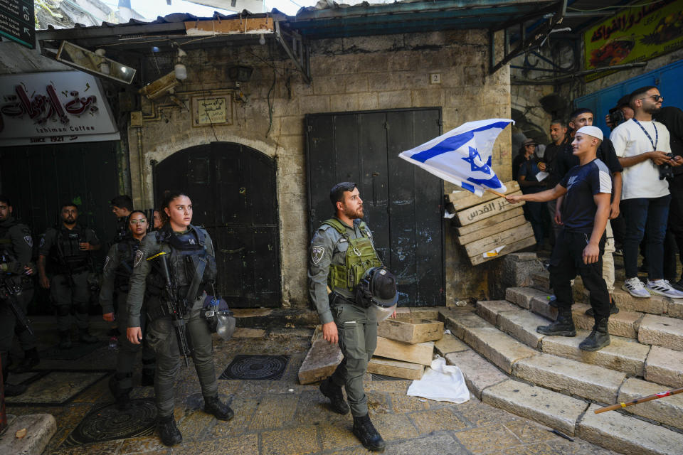 Israeli border police officers look at an Israeli as he waves a national flag during a march marking Jerusalem Day, in Jerusalem's Old City, Wednesday, June 5, 2024. (AP Photo/Ohad Zwigenberg)