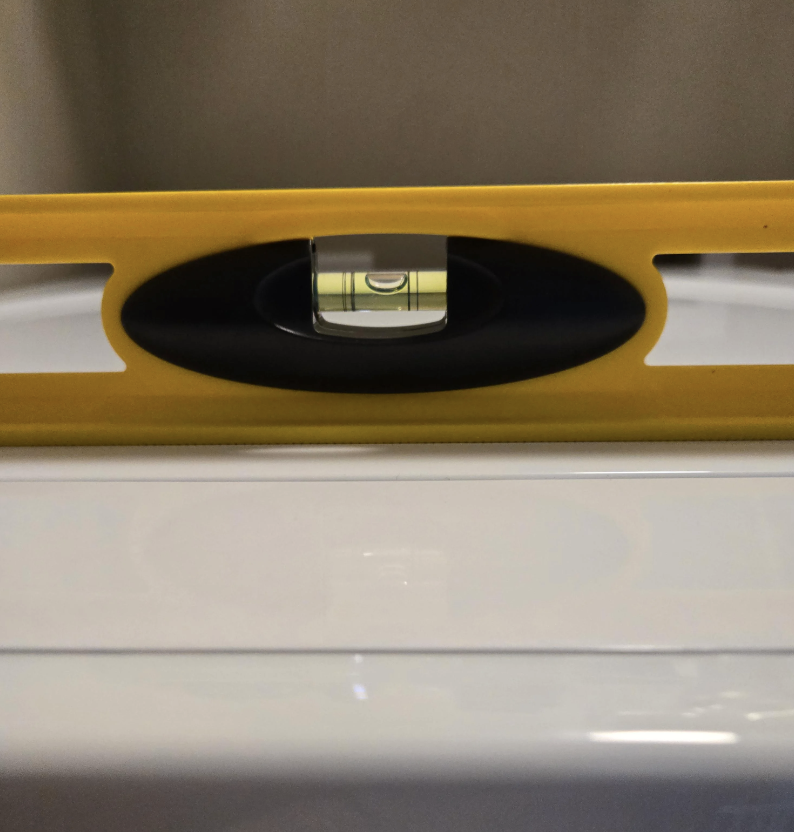 A yellow spirit level centered on a white surface indicating a balanced position