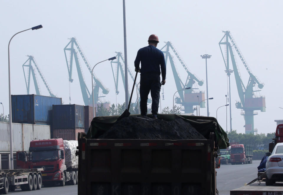 A labourer loads coal in a truck next to containers outside a logistics center near Tianjin Port, in northern China, May 16, 2019. REUTERS/Jason Lee