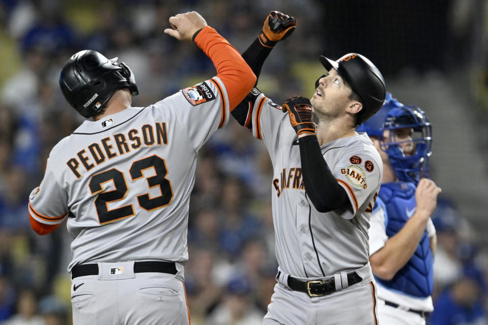 San Francisco Giants' Joc Pederson, left, celebrates with Mike Yastrzemski, front right, after Yastrzemski hit a two-run home run during the fourth inning of a baseball game against the Los Angeles Dodgers in Los Angeles, Friday, Sept. 22, 2023. Dodgers catcher Will Smith, back right, looks on. (AP Photo/Alex Gallardo)