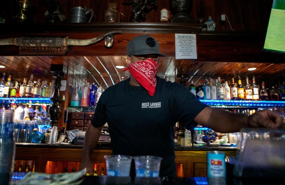 Bartender Kariel Green mixes a drink behind plexiglass at Neil's Lounge in Indio, Calif., on Friday, June 12, 2020.