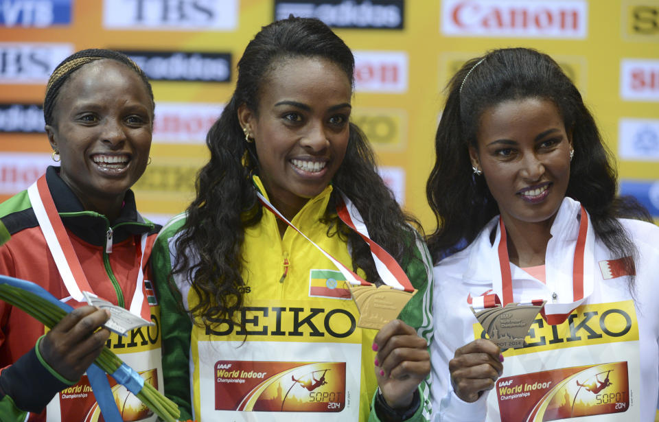 Ethiopia's gold medal winner Genzebe Dibaba is flanked by Kenya's silver medal winner Hellen Onsando Obiri, left, and Bahrain's bronze medal winner Maryam Yusuf Jamal during the ceremony for the women's 3000m at the Athletics Indoor World Championships in Sopot, Poland, Sunday, March 9, 2014. (AP Photo/Alik Keplicz)