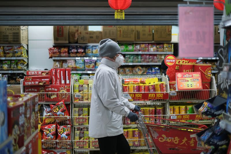 A woman wearing a face mask looks for goods at a supermarket, as the country is hit by an outbreak of the new coronavirus, in Beijing