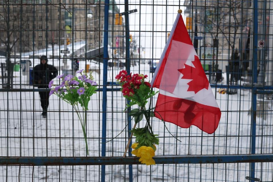 OTTAWA, ONTARIO - FEBRUARY 20: Flowers and a flag hang on a barrier fence near Parliament Hill a day after police cleared a demonstration by truck drivers opposing vaccine mandates that had been entrenched for 23 days on February 20, 2022 in Ottawa, Ontario, Much of the area in downtown Ottawa near Parliament Hill has been declared a secure zone where only residents and people who can prove they have a valid purpose for entering are allowed past checkpoints. (Photo by Scott Olson/Getty Images)