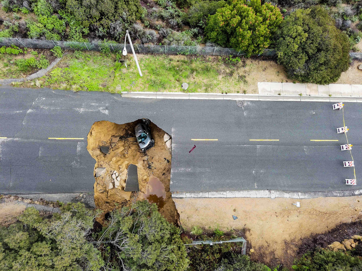 Two cars siting in a large sinkhole that opened during a day of relentless rain, Jan. 10, 2023 in the Chatsworth neighborhood of Los Angeles. (Robyn Beck/AFP via Getty Images)