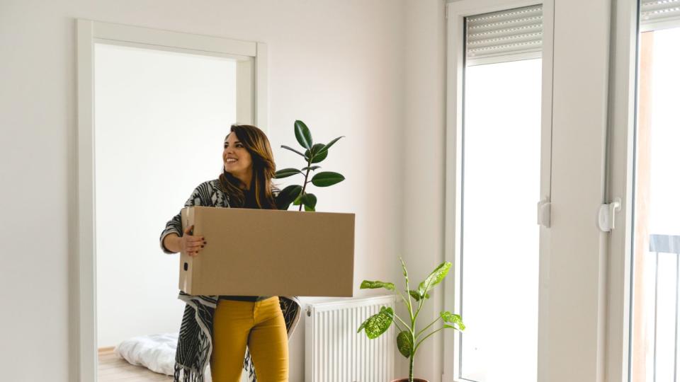 woman holding box of things in apartment