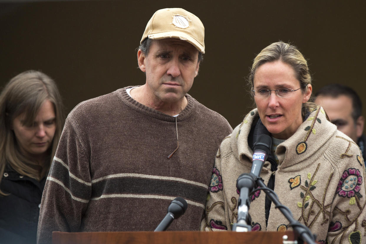 Scarlett Lewis speaks at a microphone, flanked by her husband, Neil Heslin.