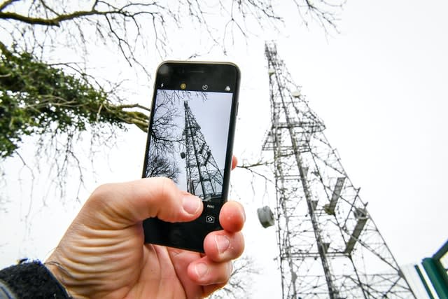 A mobile phone next to a telecoms mast